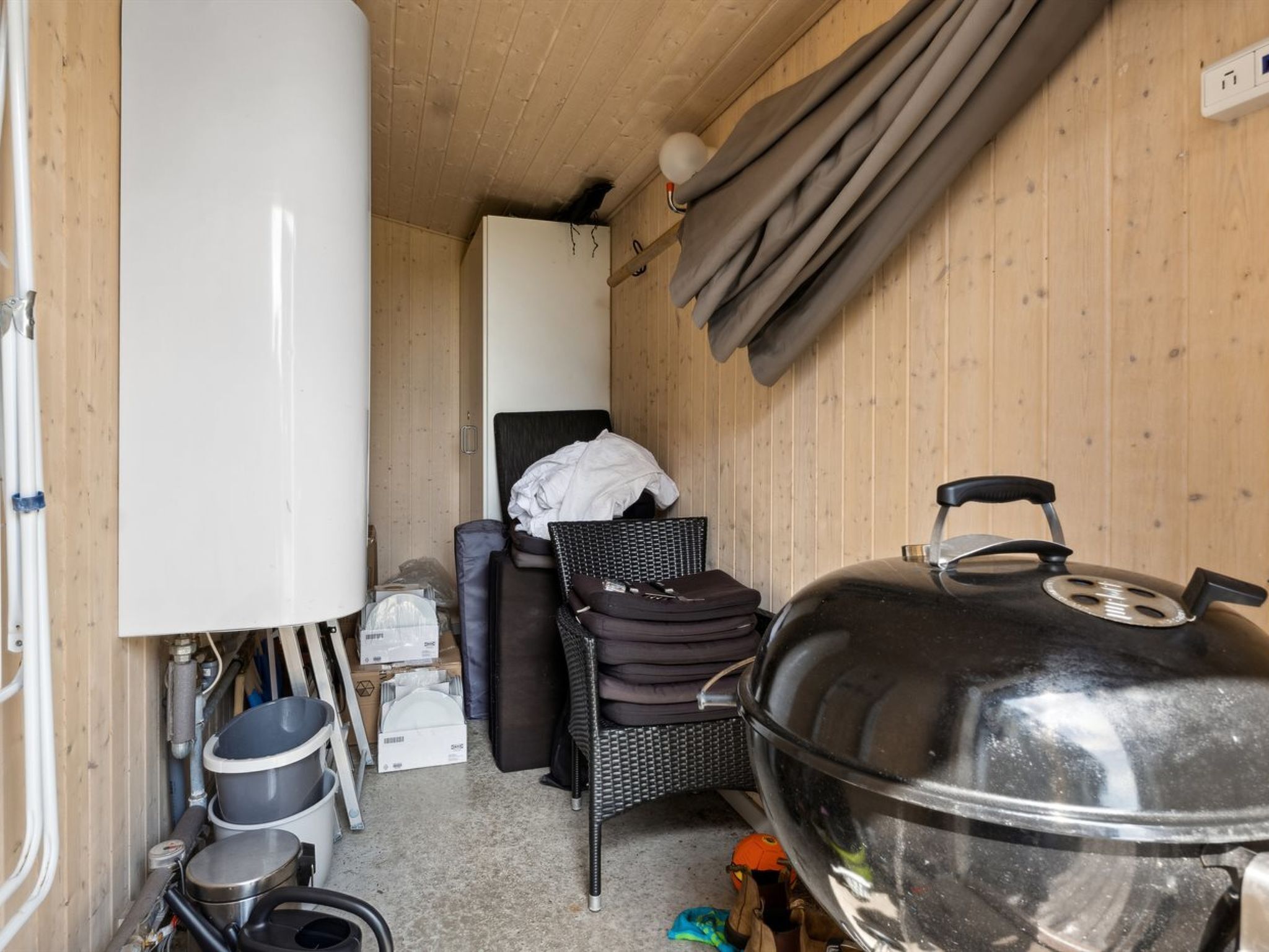 Een kleine keuken met een grote grill, een witte koelkast en een rieten stoel.