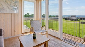 A room with wooden walls and large windows, a table, and two chairs.
