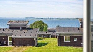 A row of wooden cabins with a view of the sea and distant hills.