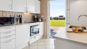 A modern kitchen with white cabinets, a built-in microwave, an oven, and a sink.