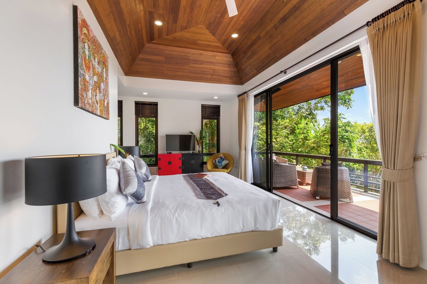 A modern bedroom with a large bed, a TV, and a balcony with outdoor furniture.