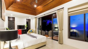 Une chambre moderne avec un grand lit, une télévision, une armoire rouge et un balcon offrant une vue sur le ciel nocturne.