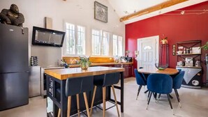 Una cocina moderna con un refrigerador negro, taburetes de bar de madera y una pared de acento roja.