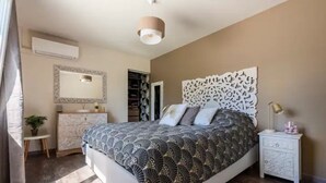 Un dormitorio con cama, mesita de noche, cómoda, espejo y un panel decorativo en la pared.
