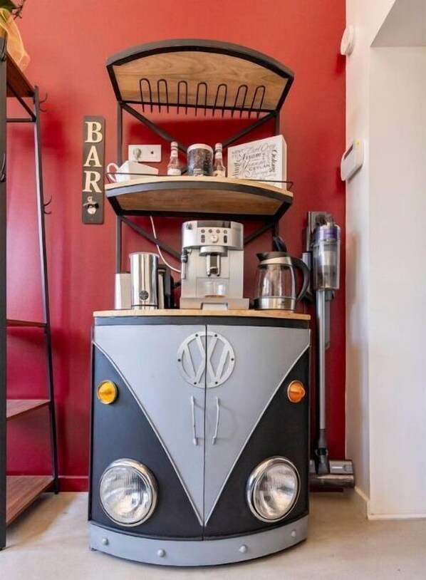 Un área de bar de estilo retro con una cafetera antigua, un molinillo de café y un dispensador de agua.
