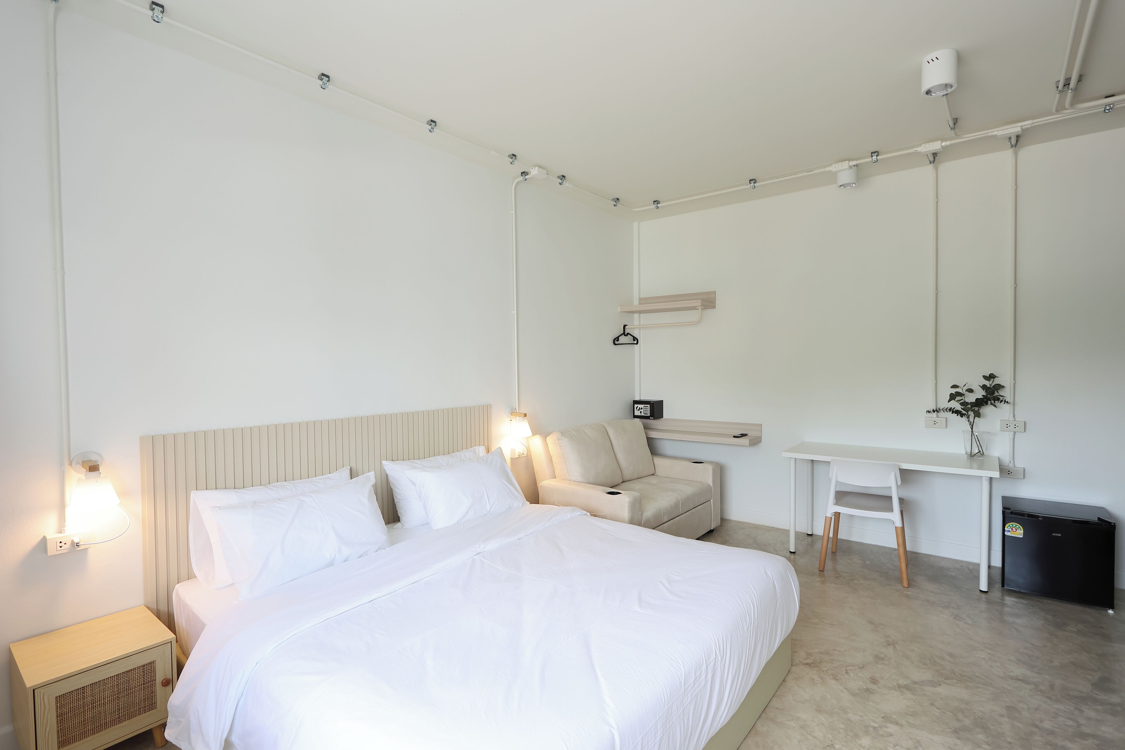 Une chambre d’hôtel moderne, dotée d’un grand lit, de tables de chevet, d’un bureau et d’une chaise.