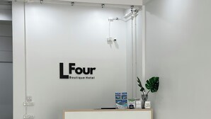 A reception area with a white desk, a wooden table, and three wicker chairs. - LFOUR  (Phuket)
