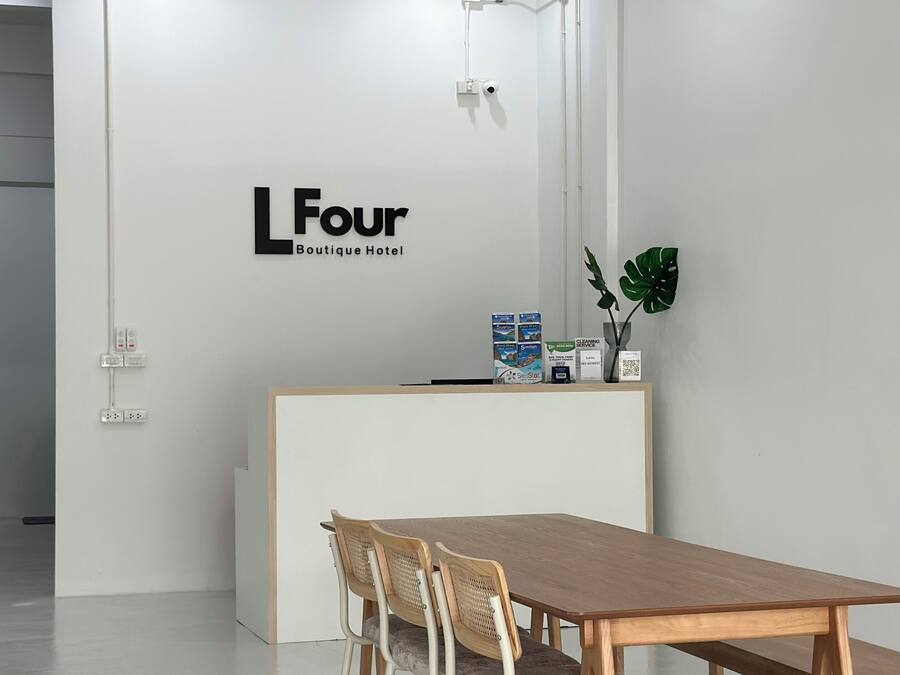 Un área de recepción con un mostrador blanco, una mesa de madera y tres sillas de mimbre.