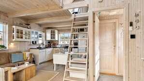 Een knus keuken in chaletstijl met houten wanden, een inbouwfornuis en een vide met een ladder.