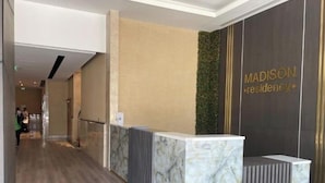 A reception area with a marble counter, a green vertical garden, and a wall with 'MADISON residency' signage. - Snug Studio With City Views, Perfect For Couples (Dubai)