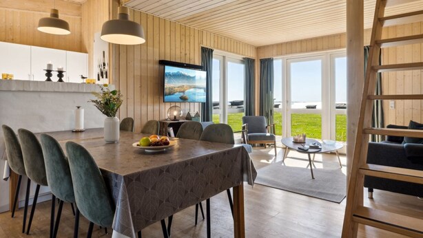 A modern dining area with a wooden table, chairs, and a television.