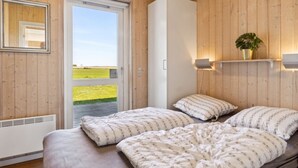 A bedroom with a bed, a wardrobe, a mirror, and a window with a view of a green field.