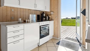 A modern kitchen with white cabinets, a stove, and a coffee maker.