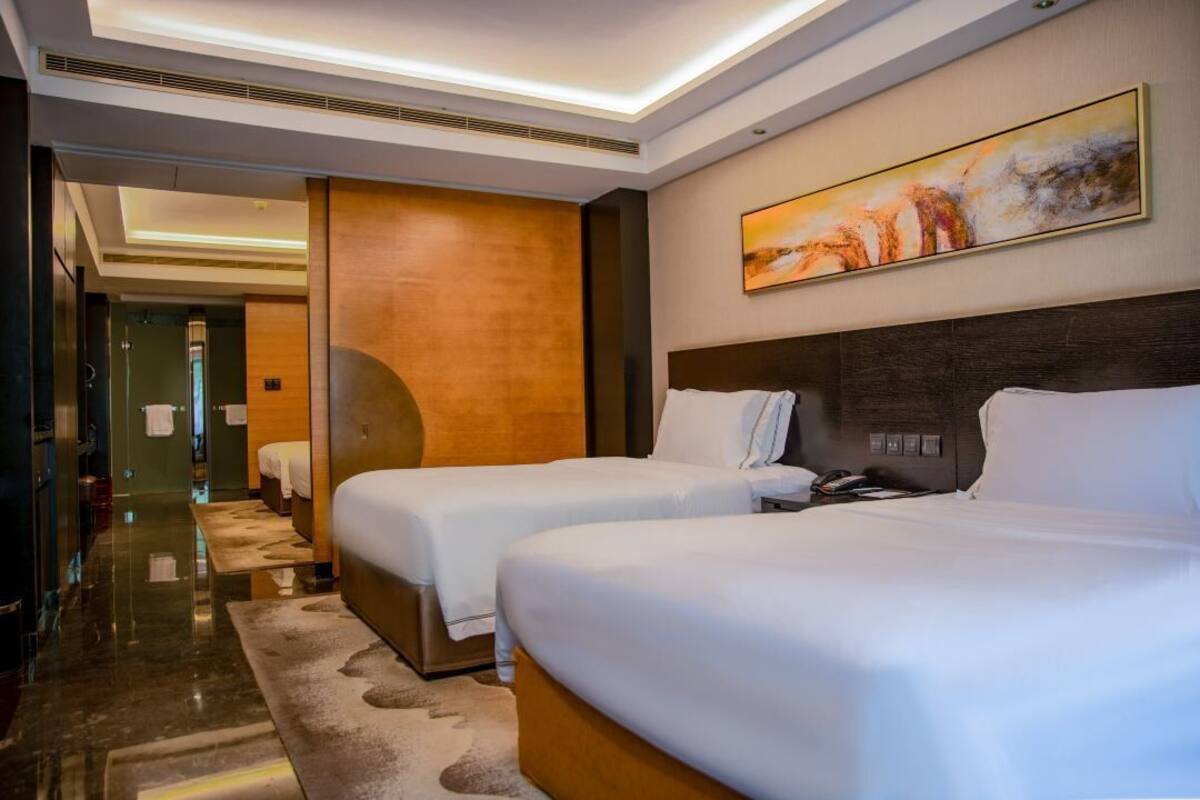 Ein Hotelzimmer mit zwei Betten, einem großen abstrakten Gemälde und einem modernen Design.