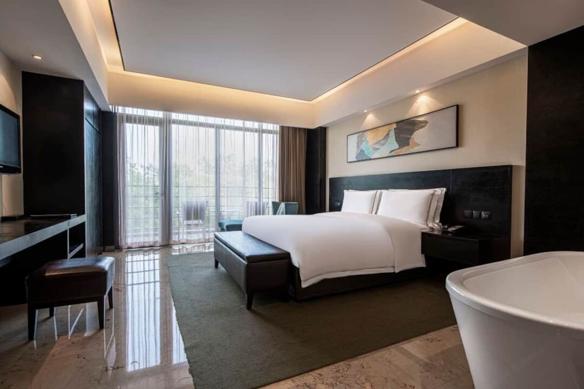 Ein modernes Hotelzimmer mit einem großen Bett, einem Schreibtisch, einem Fernseher und einer Badewanne.