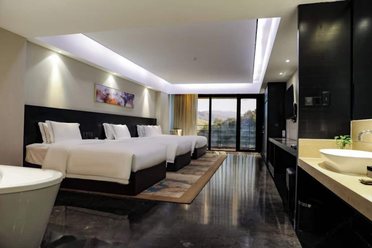 Ein modernes Hotelzimmer mit einem großen Bett, einem Badezimmer mit Waschbecken und Blick ins Freie.