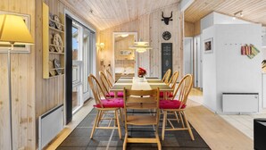 Un comedor con techo de madera, una mesa larga con sillas y un reloj fijado en la pared.