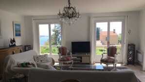 Ein Wohnzimmer mit einer Couch, zwei Sesseln, einem Fernseher und einer Chandelier.