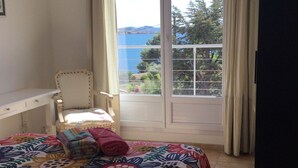 Ein Schlafzimmer mit Bett, einem Sessel und Blick ins Freie.
