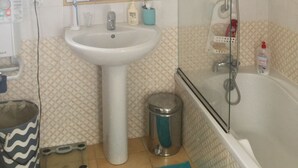 Ein Badezimmer mit Waschbecken, Spiegel, Dusche und Mülleimer.