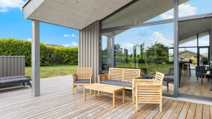 Eine Terrassenanlage im Freien mit Holzmöbeln und Glastüren zu einem Patio.