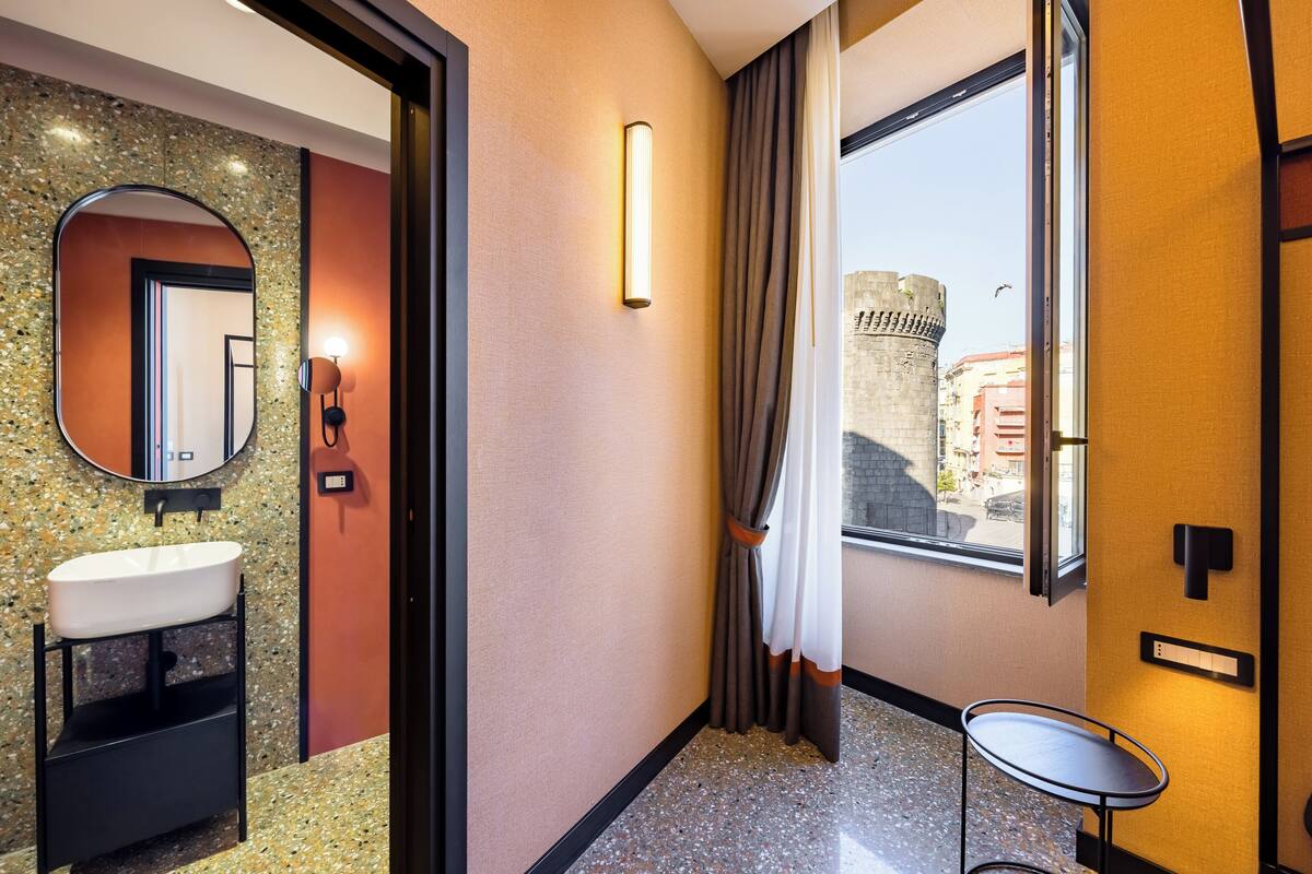 Ein modernes Badezimmer mit einem Waschbecken aus Granit, einem runden Spiegel und einem kleinen Tisch.