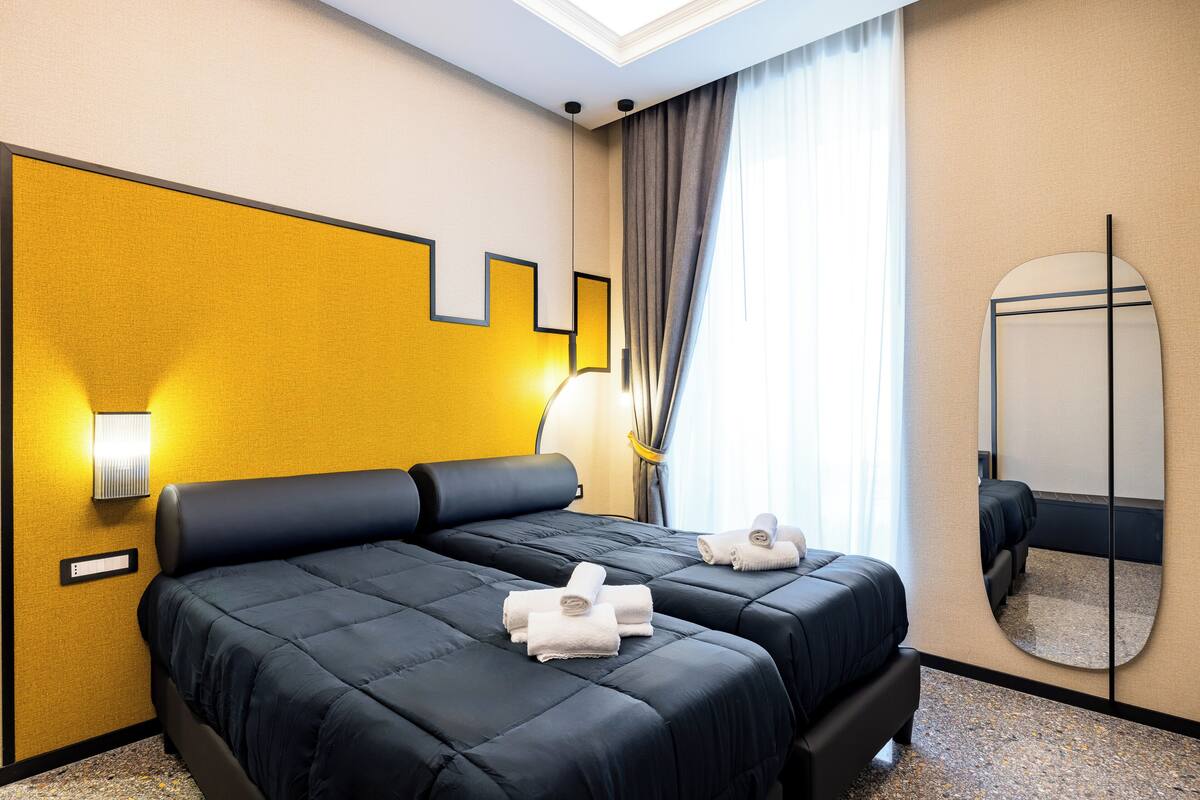 Ein Hotelzimmer mit zwei Betten, einem großen Spiegel und einer Wandleuchte.