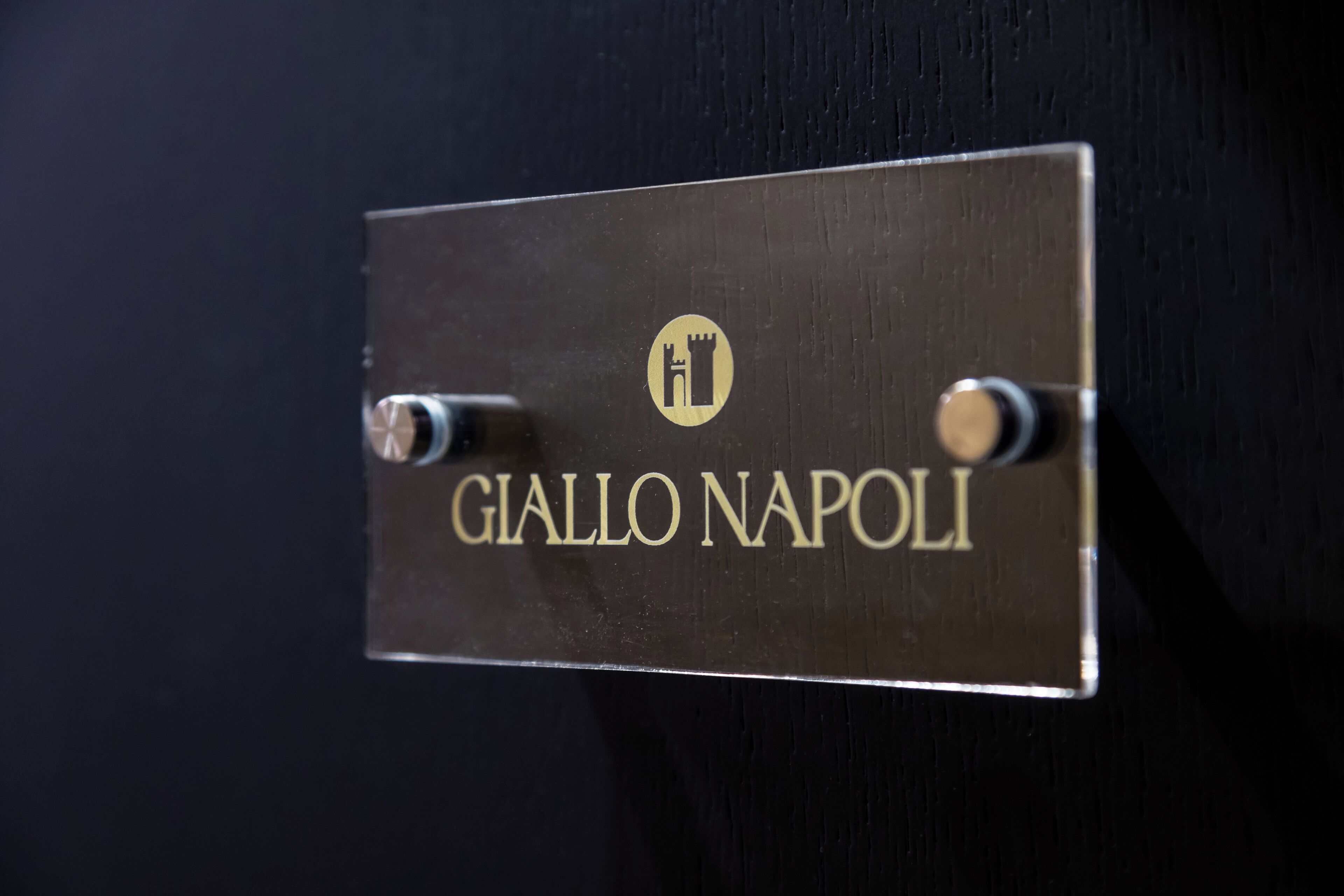 A metallic sign with the name "Giallo Napoli" and a logo.