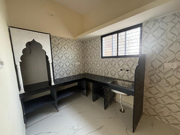 A kitchen with a black countertop, a sink, and patterned wallpaper.