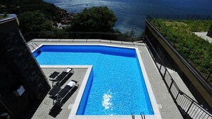 Una piscina rettangolare con vista libera su un lago e montagne sullo sfondo.