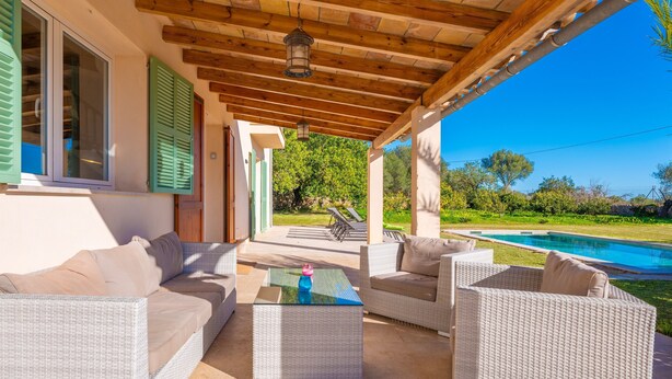 An outdoor patio with wicker furniture, a glass coffee table, and a view of a swimming pool. - Ses Set Tanques De Son Fosquet (Llucmajor)
