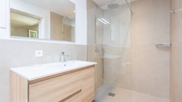 A modern bathroom with a glass-enclosed shower, a white sink, and wooden cabinetry.