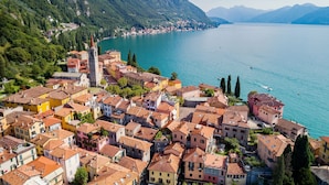 A coastal town with colorful buildings, a prominent church tower, and a clear view of the lake. - Balcone di Perledo in Perledo (Perledo)