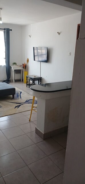 Un salon moderne avec un canapé, une table basse, un téléviseur fixé au mur et une petite table sur laquelle est posé un vase.