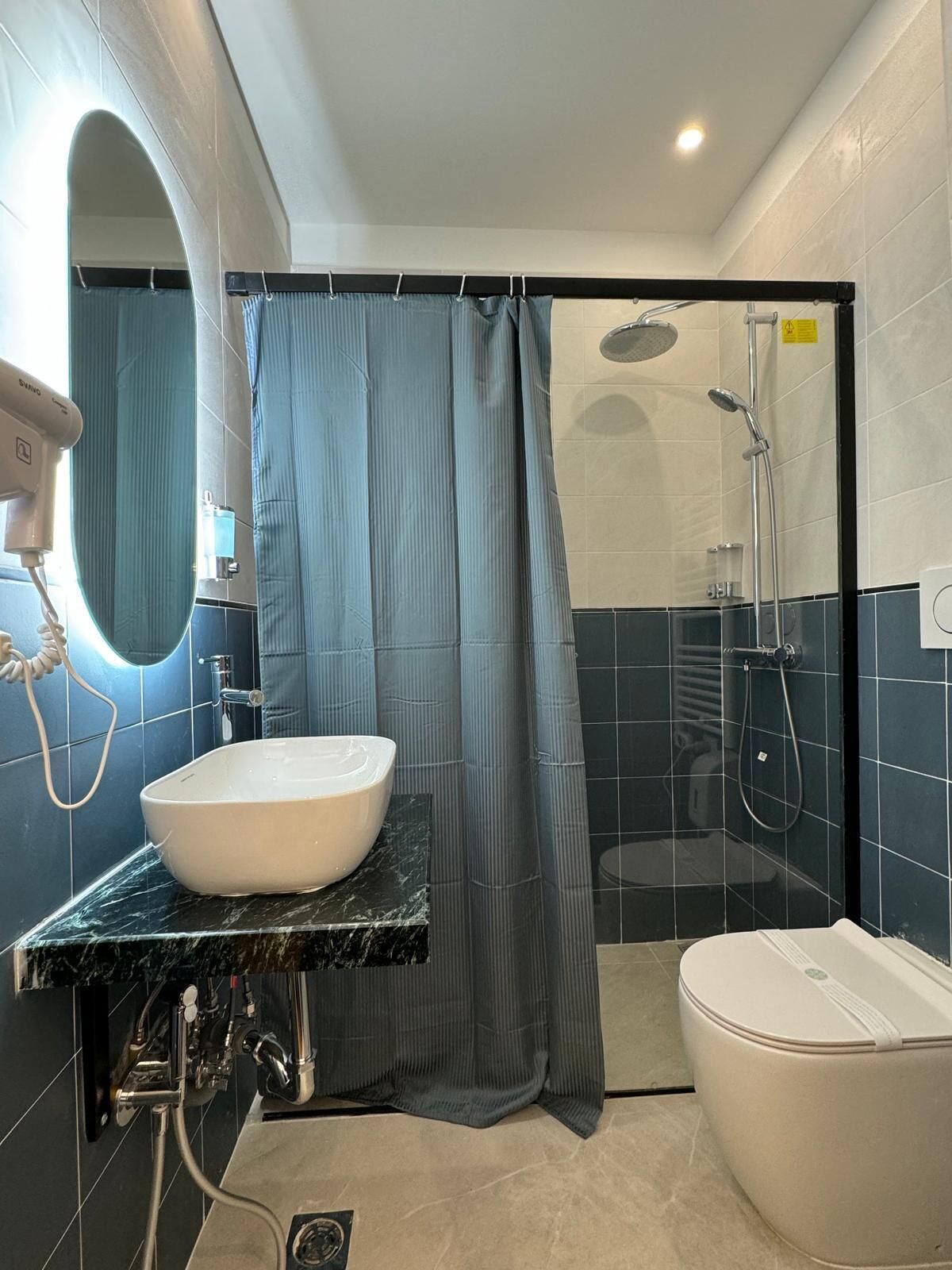 Un baño con lavamanos blanco, ducha e inodoro.