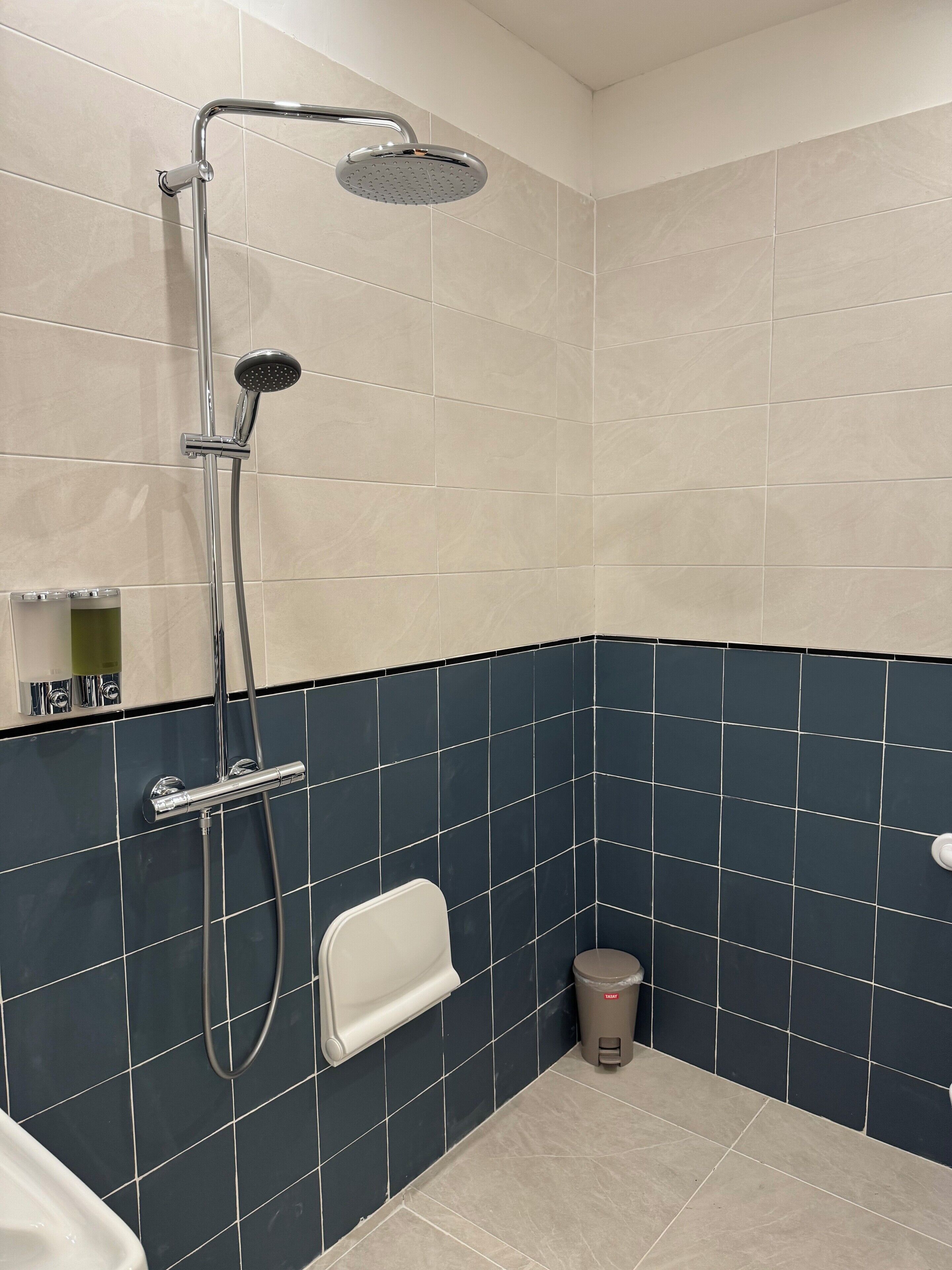 A bathroom with a shower, a toilet, and a hand dryer.