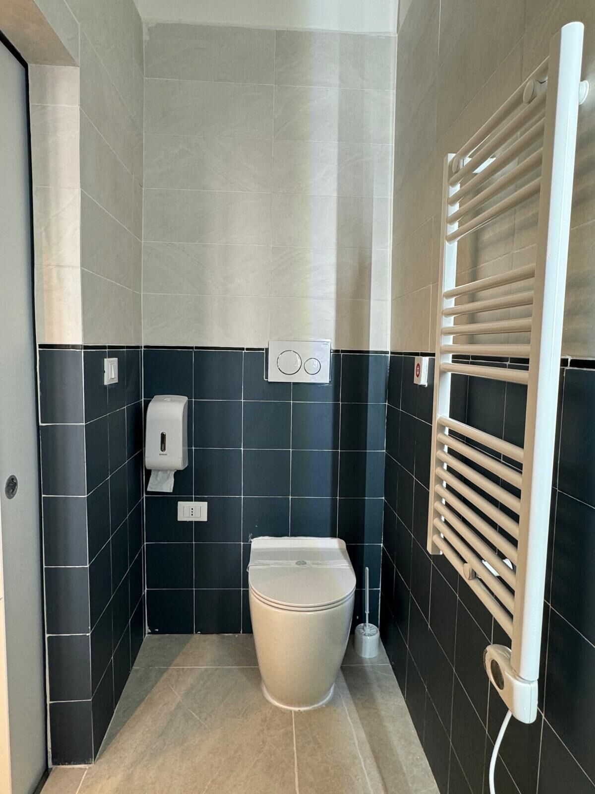 Een moderne badkamer met toilet, handdroger en handdoekrek.