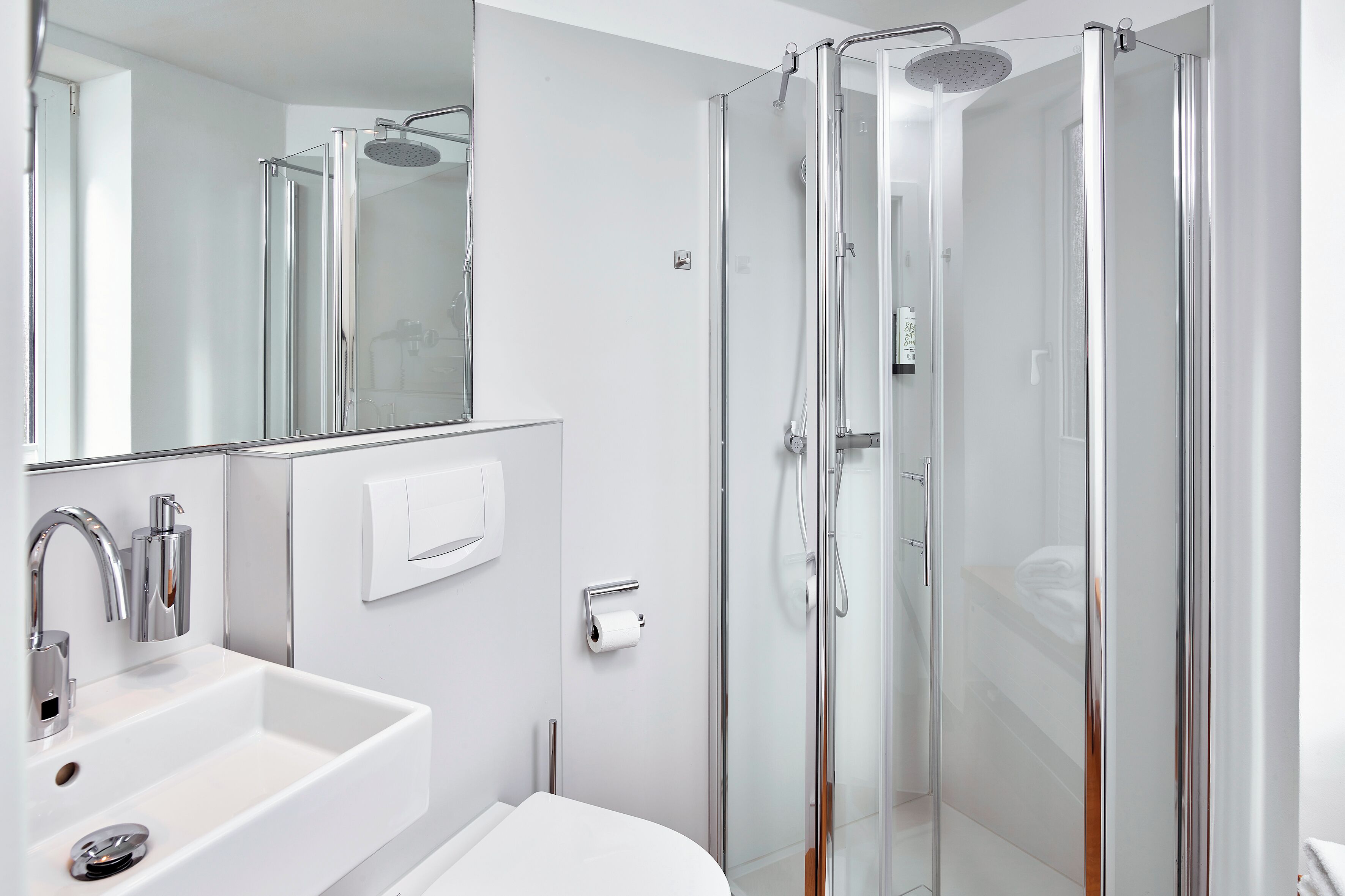 A modern bathroom with a glass-enclosed shower, a white sink, and a mirror.