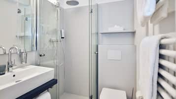 A modern bathroom with a glass-enclosed shower, a white sink, and a toilet.