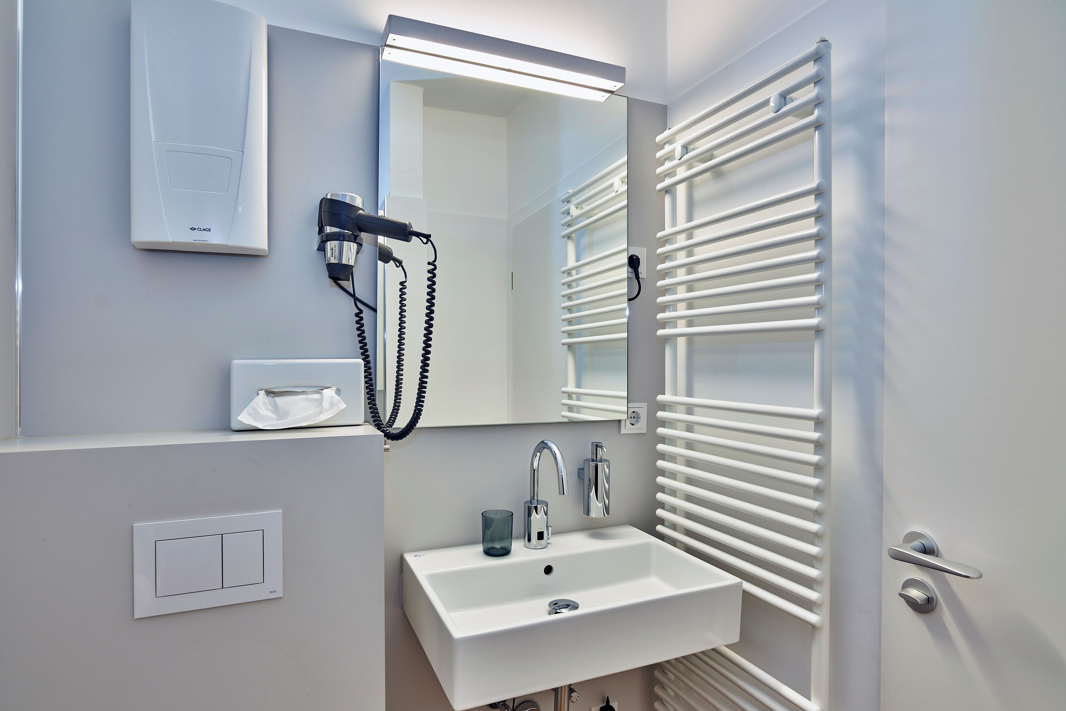 A modern bathroom with a white sink, mirror, and towel rack.