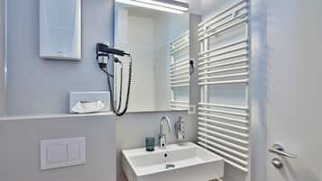 Un baño moderno con lavamanos, espejo y barra para toallas blancos.