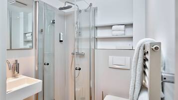 Un baño moderno con ducha de vidrio, lavamanos blanco y retrete.