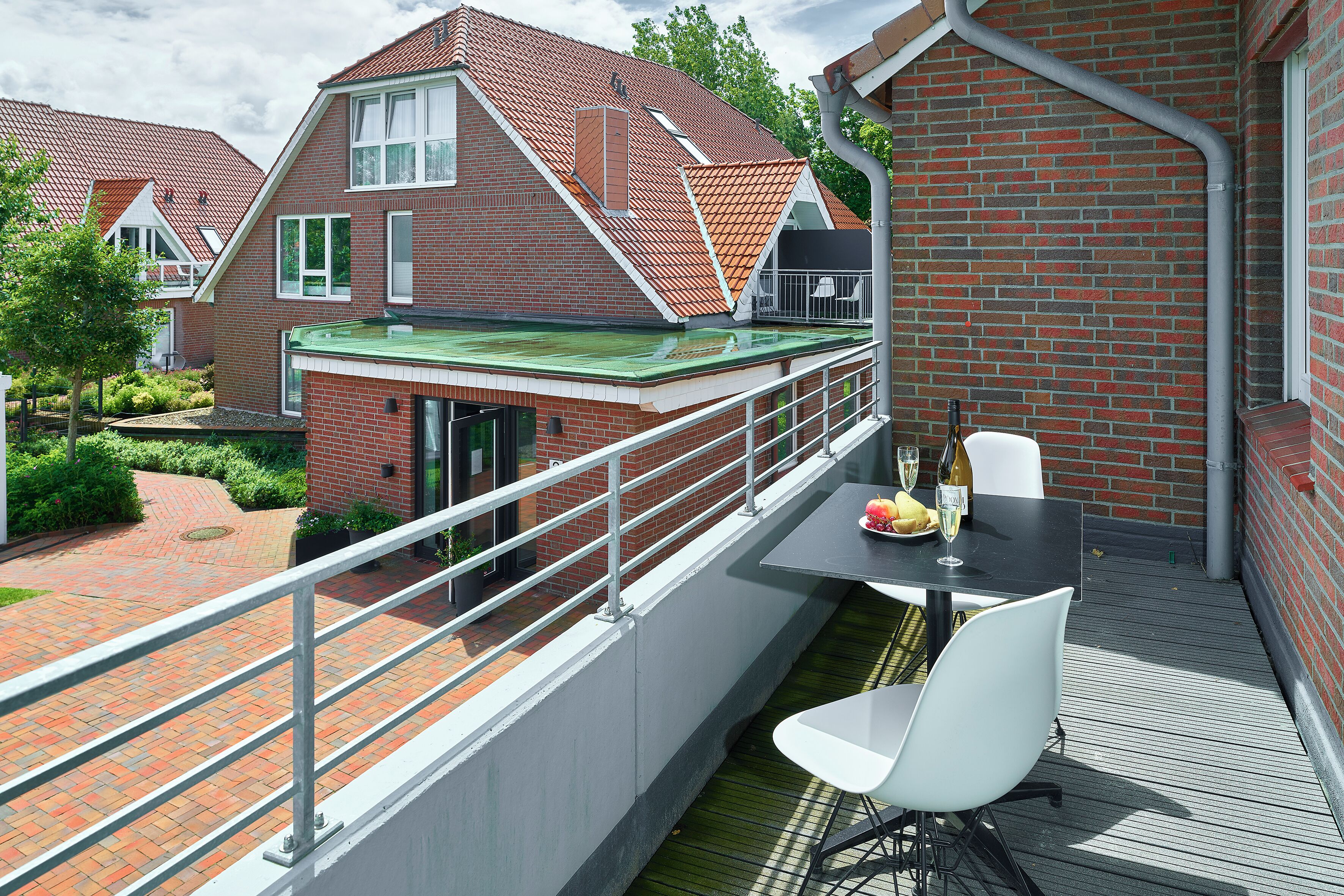 Un balcon avec une table et des chaises, un bâtiment en briques et un toit végétalisé.