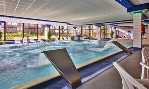 A large indoor swimming pool with multiple lanes, lounge chairs, and a hot tub area. - Aquantis Bensersiel (Esens)