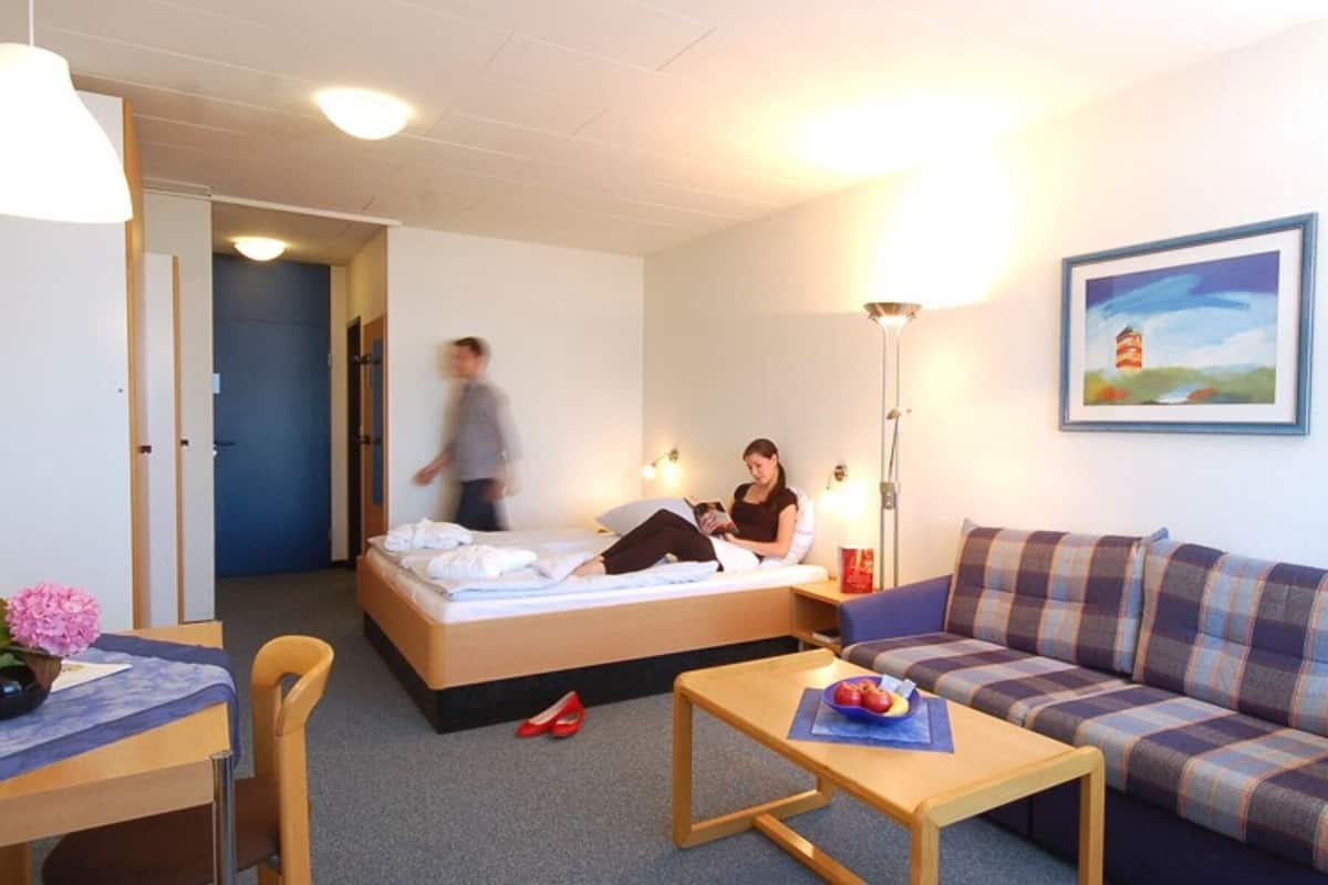 Ein Hotelzimmer mit Bett, einer Couch, einem Tisch und einem Bild an der Wand.