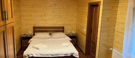 A wooden-paneled bedroom with a double bed, bedside tables, and a radiator.