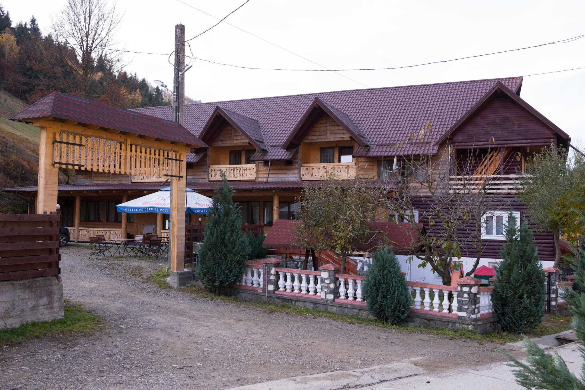 A traditional wooden building with multiple balconies and a gravel driveway.