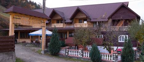 A traditional wooden building with multiple balconies and a gravel driveway.