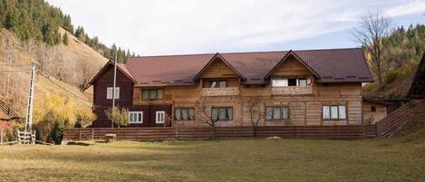 Un bâtiment en bois doté d’un toit en pente, de nombreuses fenêtres et d’une cour clôturée.