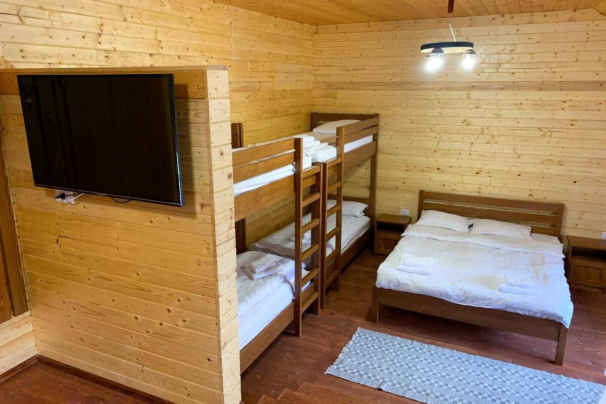 A wooden cabin room with bunk beds, a television, and a ceiling light.